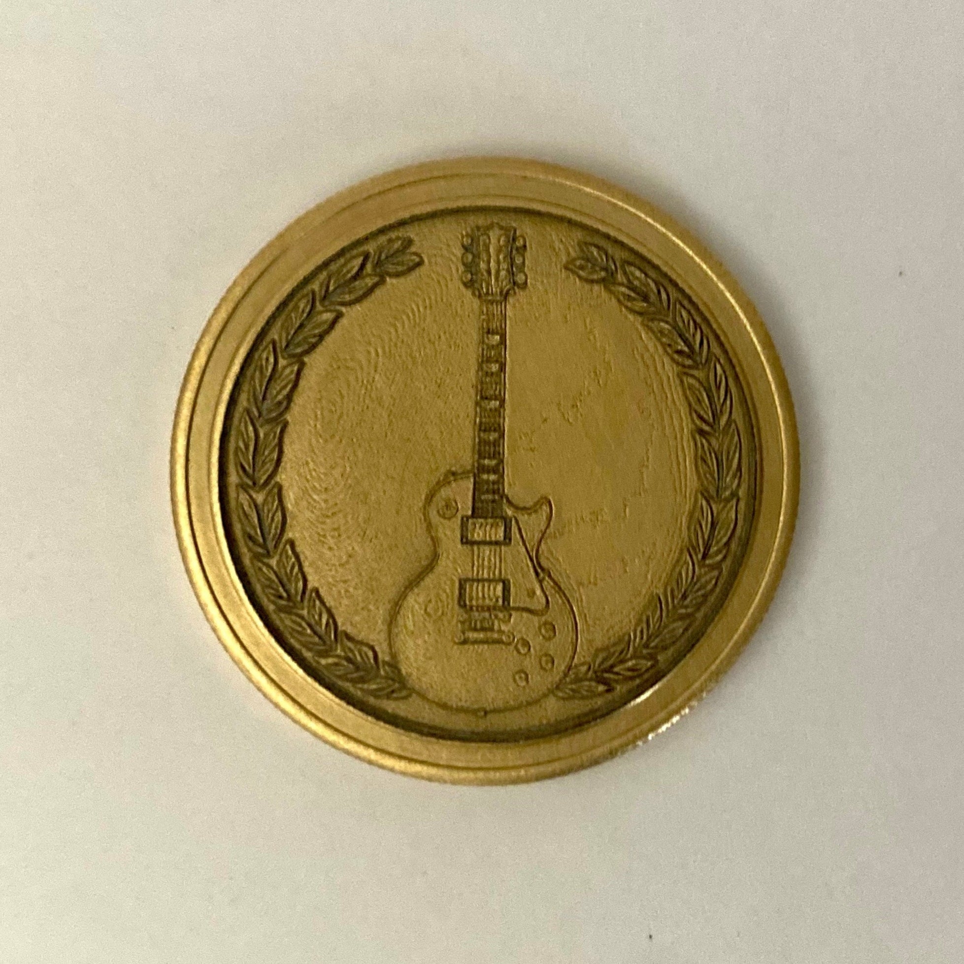 Brass coin with a guitar design on a white background